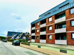 un edificio di mattoni rossi con auto parcheggiate accanto a una strada di Eidum 209 -strandnah- a Westerland