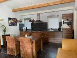 een keuken met een houten tafel en een eetkamer bij Ruime en comfortabele bungalow aan bosrand in Lage Mierde
