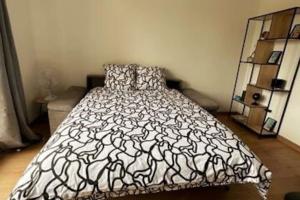 ein Schlafzimmer mit einem Bett mit einer schwarz-weißen Bettdecke in der Unterkunft L'escale, Studio proche Gare Melun avec parking privé in Dammarie-les-Lys