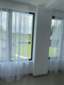 a room with white curtains and a large window at La Scoabă in Baia de Fier