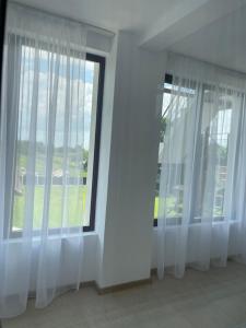 a room with white curtains and a large window at La Scoabă in Baia de Fier