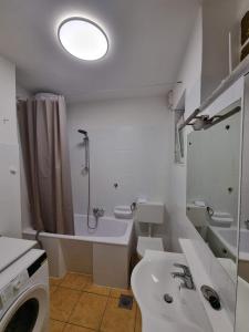 een badkamer met een wastafel, een bad en een wasmachine bij F13 Apartment in Pula