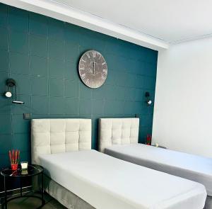 two beds in a room with a clock on the wall at Modernes Apartment am Marktplatz in Wesel