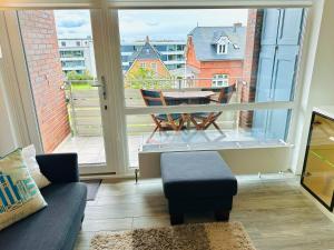 ein Wohnzimmer mit einem Sofa und einem Balkon mit einem Tisch in der Unterkunft Eidum 209 -strandnah- in Westerland