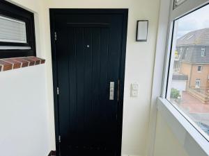 eine schwarze Tür in einem Raum mit einem Fenster in der Unterkunft Eidum 209 -strandnah- in Westerland