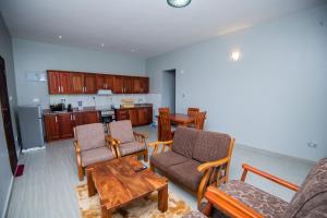 ein Wohnzimmer mit Stühlen und einem Tisch sowie eine Küche in der Unterkunft Lubowa View Apartments in Kampala