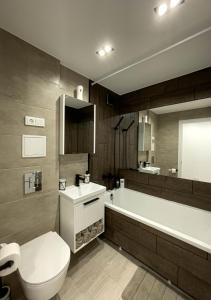 a bathroom with a toilet and a tub and a sink at Welcome City Centre Apartments in Klaipėda