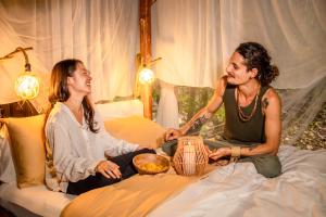 dos mujeres sentadas en una cama hablando entre ellas en AWAKEN Amazonian Healing Resort ALL INCLUSIVE, en Iquitos