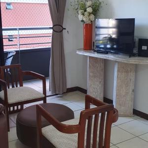 - un salon avec une table, une télévision et des chaises dans l'établissement Confortável apartamento a 100 m Beira Mar - Edifício Zen Residence, à Fortaleza