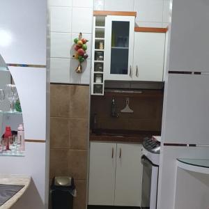 - une cuisine avec des placards blancs et un bol de fruits dans l'établissement Confortável apartamento a 100 m Beira Mar - Edifício Zen Residence, à Fortaleza