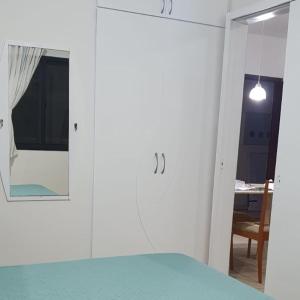Cette chambre blanche comprend un lit et un miroir. dans l'établissement Confortável apartamento a 100 m Beira Mar - Edifício Zen Residence, à Fortaleza