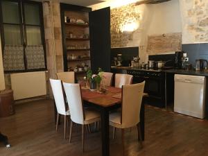a kitchen with a wooden table and white chairs at Townhouse 26 Chambres d'Hôtes Civray Hotel in Civray