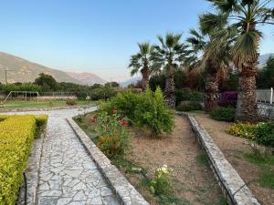 a garden with palm trees and a stone path at Villa Kostoula Mini house in Karavomylos