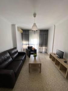 a living room with a black leather couch and a table at Piso en la puntilla in El Puerto de Santa María