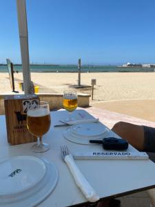 una mesa con dos vasos de cerveza en la playa en Piso en la puntilla, en El Puerto de Santa María