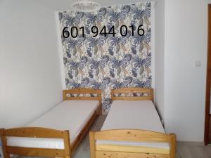 two beds in a room with a clock on the wall at Kwatery UMARIOLl in Władysławowo