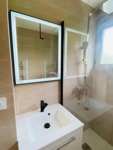 La salle de bains est pourvue d'un lavabo blanc et d'un miroir. dans l'établissement Cosy T4 75m2 charmant près de La Défense Paris, à Rueil-Malmaison