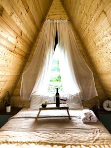 Una cama con ventana con una botella de vino. en Cottage Rest in kazbegi en Stepantsminda