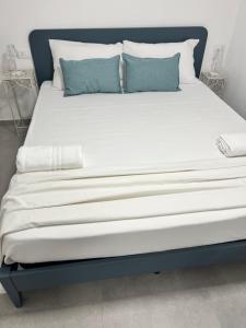 un grande letto con lenzuola bianche e cuscini blu di Cisternone Suites a Formia