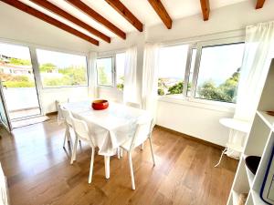 a dining room with a white table and windows at Villa Binibaquet in Binibeca