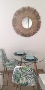 ein Tisch und zwei Stühle und ein Spiegel an der Wand in der Unterkunft Studio équipé Clim TV Wifi in Saint-Denis