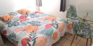 a couch with a colorful flowered blanket on it at Studio équipé Clim TV Wifi in Saint-Denis