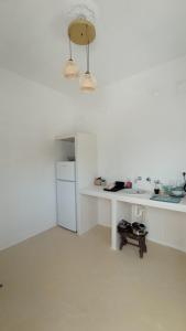 a white kitchen with a counter and a refrigerator at suite diminutif 2 in Adamas