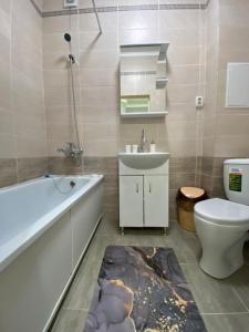 a bathroom with a tub and a toilet and a sink at 1 комнатная квартира ЖК Альтаир в центре города in Aktobe