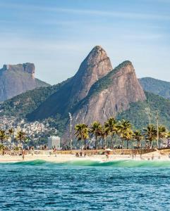 a beach with palm trees and a mountain in the background at Charme Copa Retreat próximo ao Copacabana Palace in Rio de Janeiro