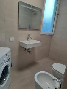 ein Badezimmer mit einem Waschbecken, einem WC und einer Waschmaschine in der Unterkunft Villa Bega in Borsh