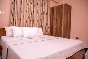 een slaapkamer met een wit bed en een houten hoofdeinde bij Executive One Bedroom Furnished Apartment in Accra in Accra