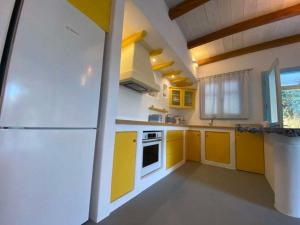 a kitchen with yellow cabinets and a white refrigerator at Actaea Villa in Alonnisos