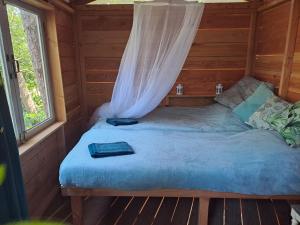 Cama en una cabaña de madera con mosquitera en Boomhut en Rijsbergen