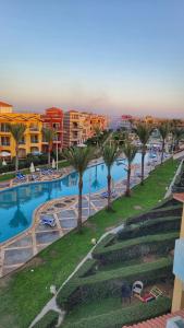 a view of a swimming pool with palm trees and buildings at Porto Matrouh for FAMILIES ONLY in Marsa Matruh