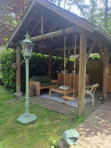 a wooden pergola with a bench and a table at Boomhut in Rijsbergen