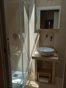 a bathroom with a sink and a glass shower at La casetta Guest House Oristano in Oristano