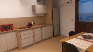 a kitchen with a sink and a table with a microwave at La casetta Guest House Oristano in Oristano