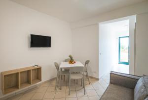 Una sala de estar con una mesa y un televisor en una pared. en Magico Apartments - 450m dalla spiaggia, en Capo dʼOrlando