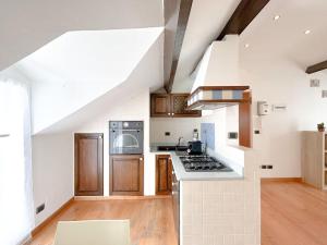 a kitchen with white walls and wooden cabinets and a stove at [Elegante mansarda] 300mt dal mare - Centro - WiFi in Savona