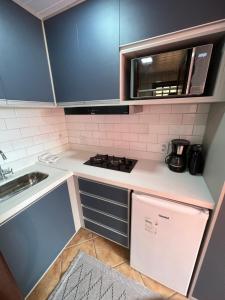 a small kitchen with a stove and a microwave at Flat Pé na Areia Cabo Frio in Cabo Frio
