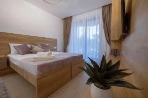 a bedroom with a bed and a potted plant at Purple Luxury Apartment Lake On in Mamaia