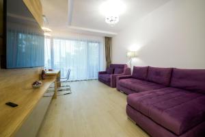 a living room with a purple couch and a table at Purple Luxury Apartment Lake On in Mamaia