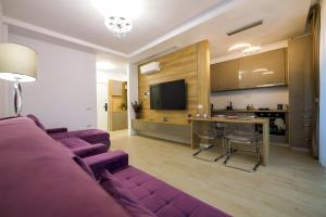 a living room with a purple couch and a kitchen at Purple Luxury Apartment Lake On in Mamaia