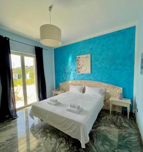 1 dormitorio con 1 cama grande y pared azul en Villa Liberti, en Castellabate
