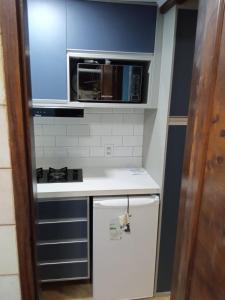 a small kitchen with a microwave and a refrigerator at Flat Pé na Areia Cabo Frio in Cabo Frio
