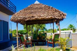 a large straw umbrella with two chairs and a table at Résidence Riziq villa 2 in Nosy Be