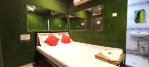 a green room with a bed with red pillows at Hotel Janata in Mumbai