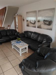 a living room with a black leather couch and a table at Hartenbos huisie in Hartenbos