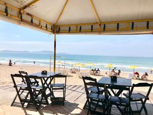 two tables and chairs in front of the beach at Flat Pé na Areia Cabo Frio in Cabo Frio
