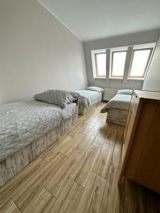 a bedroom with two beds and two windows at Apartamenty Firfas Rodzinny 11 in Bydgoszcz